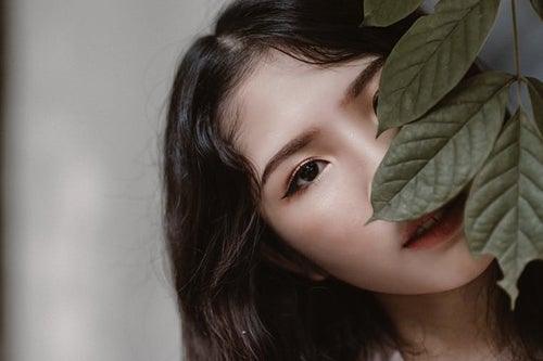 woman hiding behind a large leafy plant