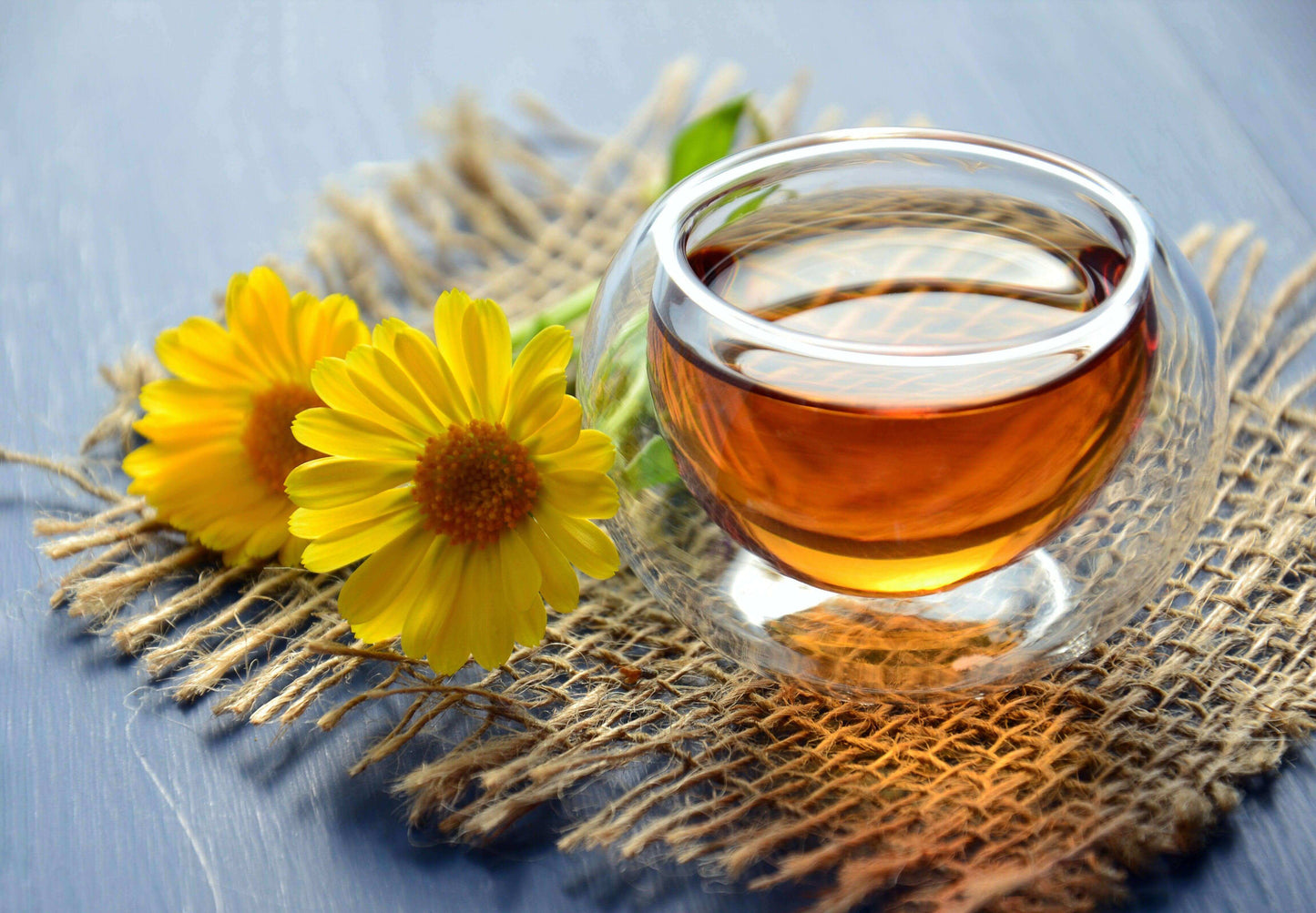 glass tea cup filled with tea and daisy on tea mat