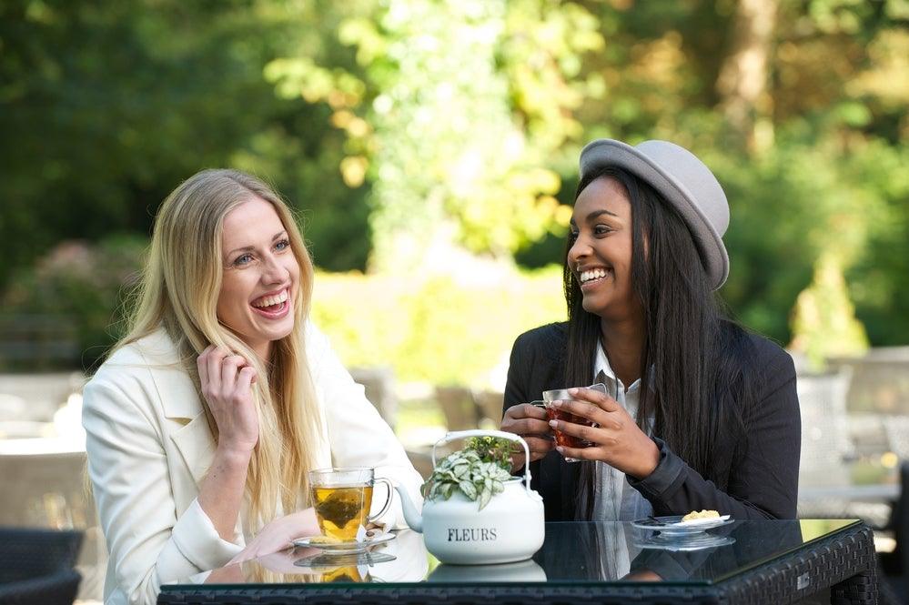 Two women at a table drinking tea outside