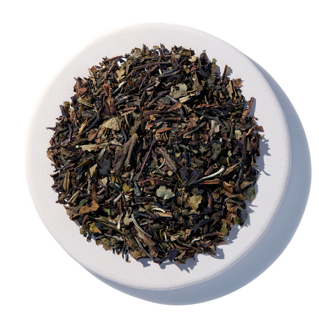 Dry tea leaves on a white plate with a white background